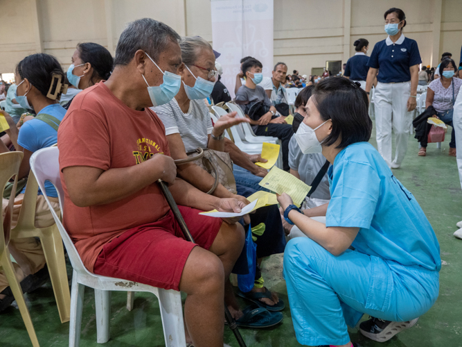 Tzu Chi International Medical Association doctor Bea Ang assists a patient.