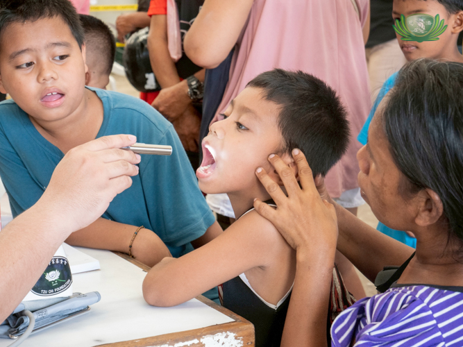 A child opens his mouth for a check-up during the Tzu Chi mini-medical mission.