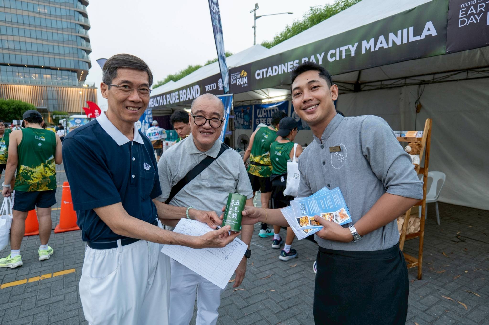 (From left) Tzu Chi volunteers Johnny Cheng and Raul Ting went around the race village distributing Tzu Chi coin banks to the various exhibitors. 