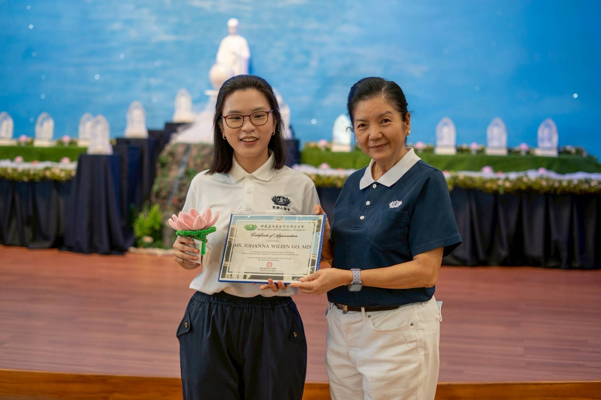 Tzu Chi Head Volunteer for the Educational and Medical Assistance Programs Rosa So (right) presents Charity Day guest speaker Dr. Johanna Wileen Go with a certificate of appreciation and a handcrafted lotus flower from Tzu Chi scholars. 