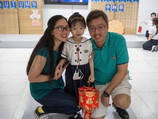 A family takes a photo while presenting their handmade lantern. 