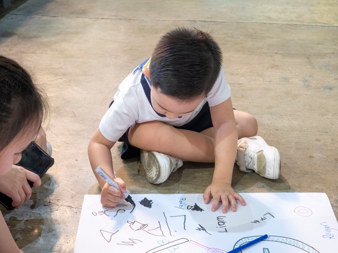 A student channels his inner creativity, decorating the banner with his and his classmates’ names.