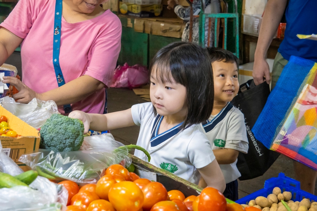 A pre-kindergarten student checks out the broccoli sold by the vendor.