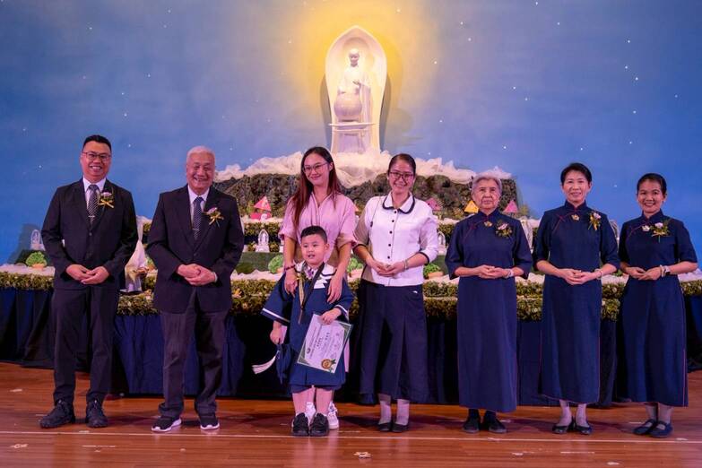 Nancy Uy (third from left) poses with son Gavin as he receives his moving-up certificate from Tzu Chi commissioners.