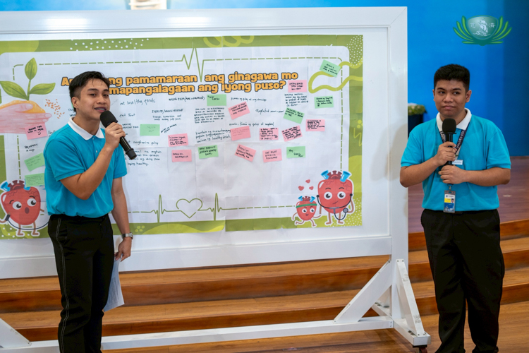 Tzu Chi scholars and Charity Day hosts Rayniel Manansala (left) and Leandro Peter Joshua Taton read notes on a wall that asks, “What do you do to take care of your heart?”