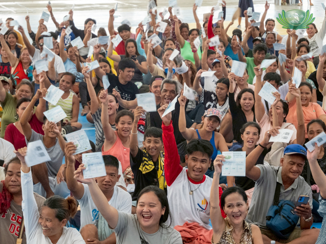 Beneficiaries cheer at the announcement that they would receive cash aid in addition to 25-kg rice and assorted groceries.