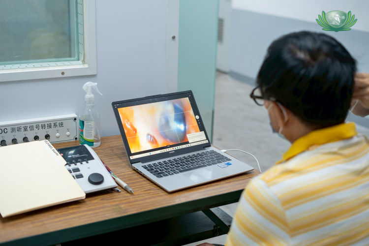 During an ear examination, Larry Velasquez, former Tzu Chi compliance officer and head of housekeeping, watches images of his inner ear from a laptop screen.