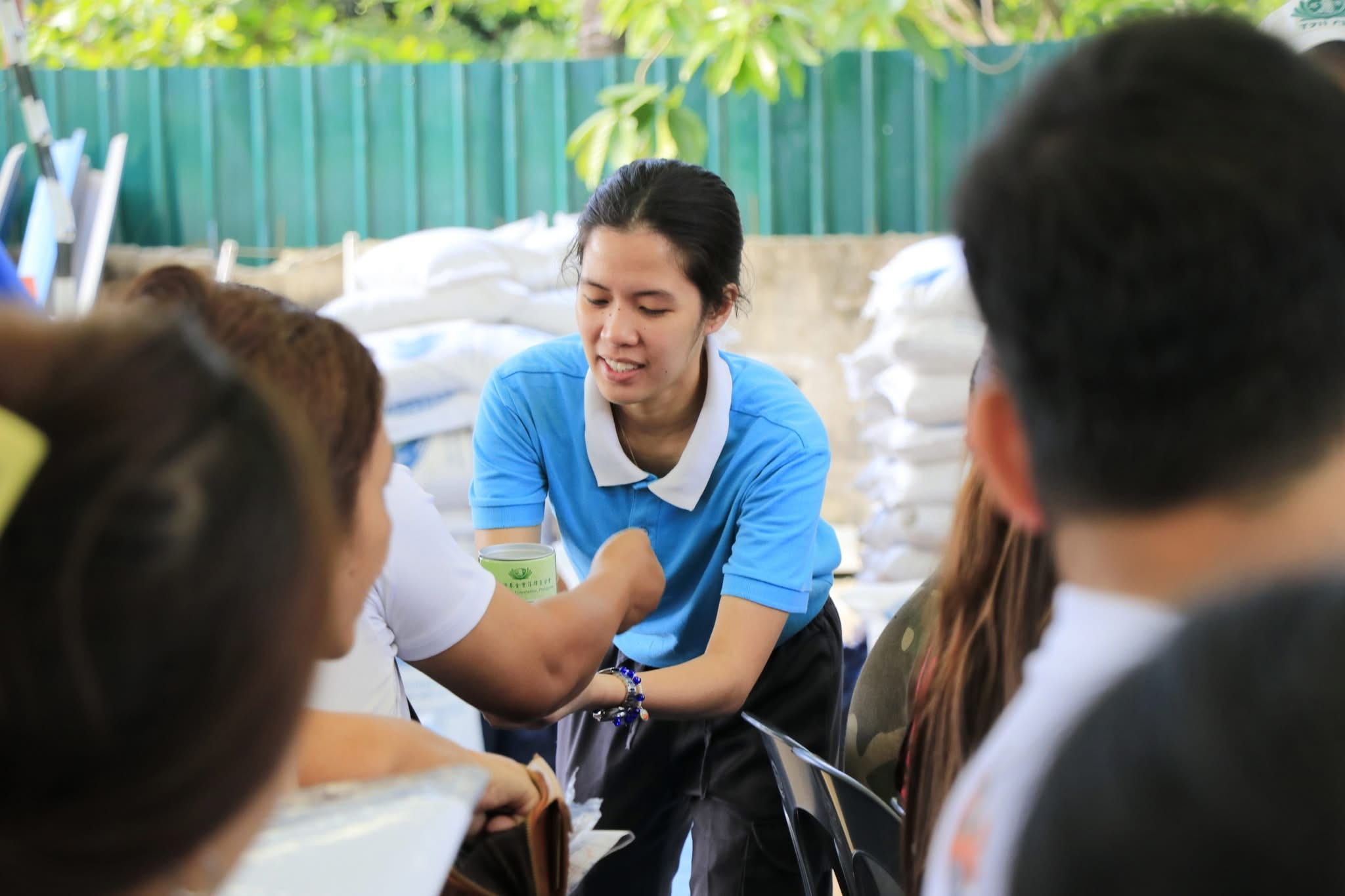 At a distribution of relief goods, Gwen Nicole Loyao accepts coin donations from beneficiaries. 