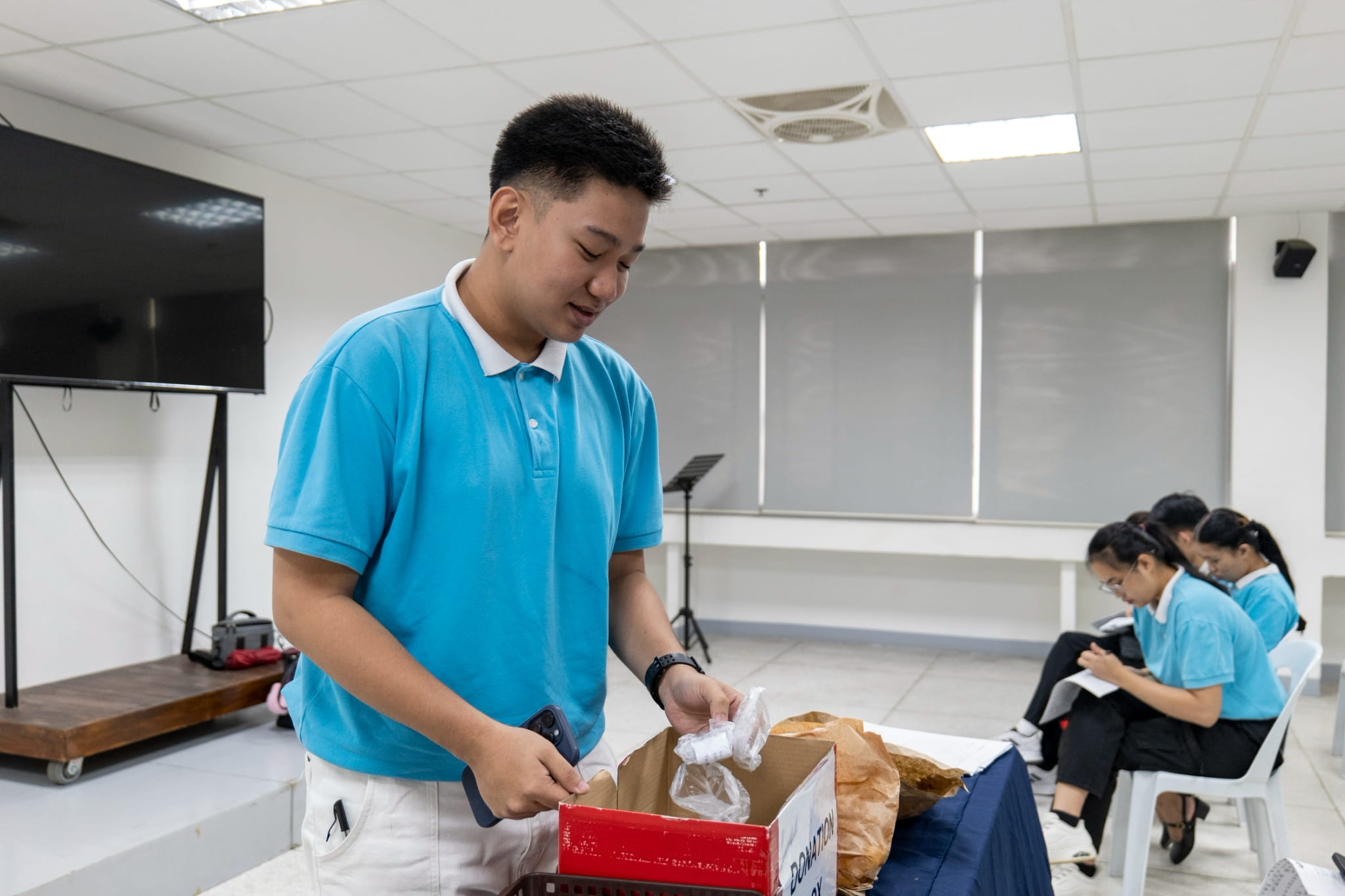 While waiting for their exit interviews, scholars at a holding area drop their pledges for Davao Occidental earthquake victims in a donation box. 