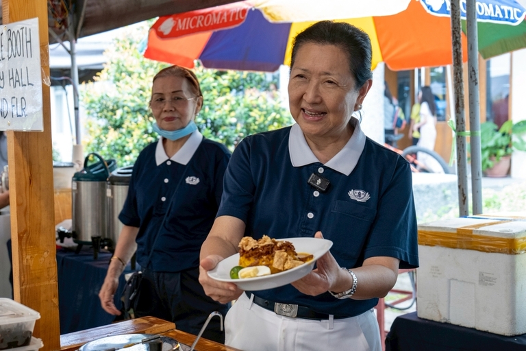 Tzu Chi kitchen head Sally Yuñez holds up a plate of palabok, a popular Filipino noodle dish whose vegetarian version includes tofu, kelp, veggie meat, vegetarian fish sauce, spices, and an egg for non-vegans.