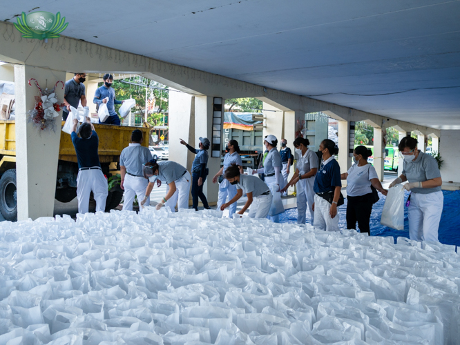 Volunteers unload a truck with sacks of grocery items then set them up before being claimed by beneficiaries.  【Photo by Daniel Lazar】