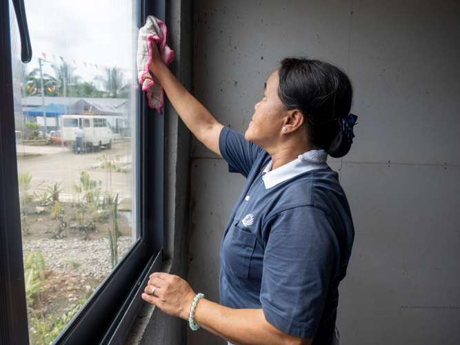 A Tzu Chi volunteer helps by cleaning the windows of the recipients’ homes.