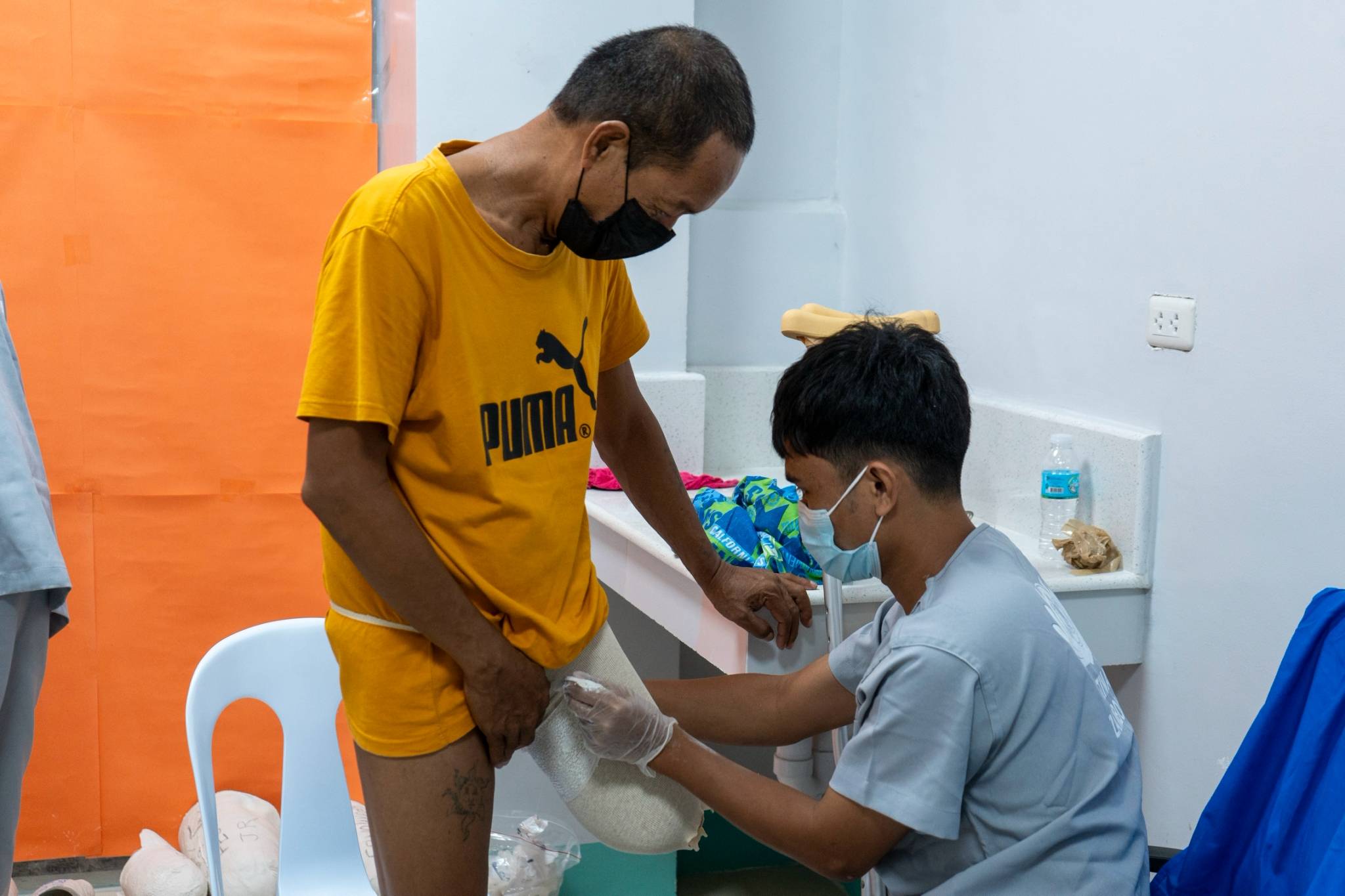 An above-the-knee amputee stands still as he is measured for a Jaipur foot prosthesis. 