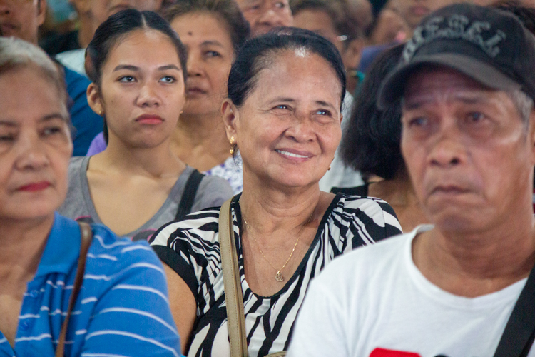 A beneficiary happily smiles while waiting for the distribution.