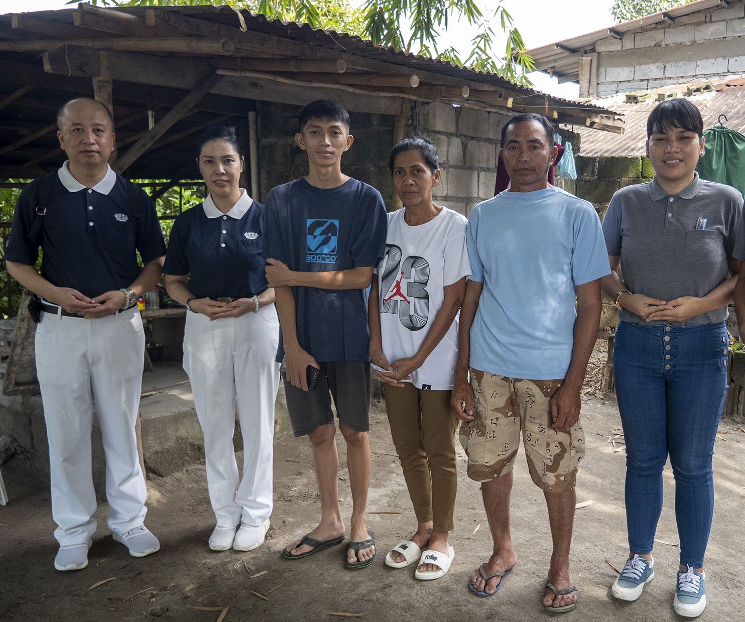 Tzu Chi volunteers and staff pose for a group photo with Ron Velasquez's mother and father following their home visit.