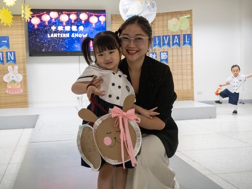 A parent poses for a photo with her daughter while showing off their creative lantern. 