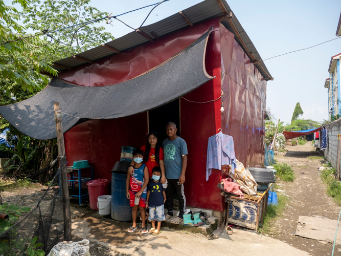 The Telecio family gather for a photo in front of their improvised house made of galvanized iron and wood, where they currently reside after moving from a demolished house and a temporary apartment.