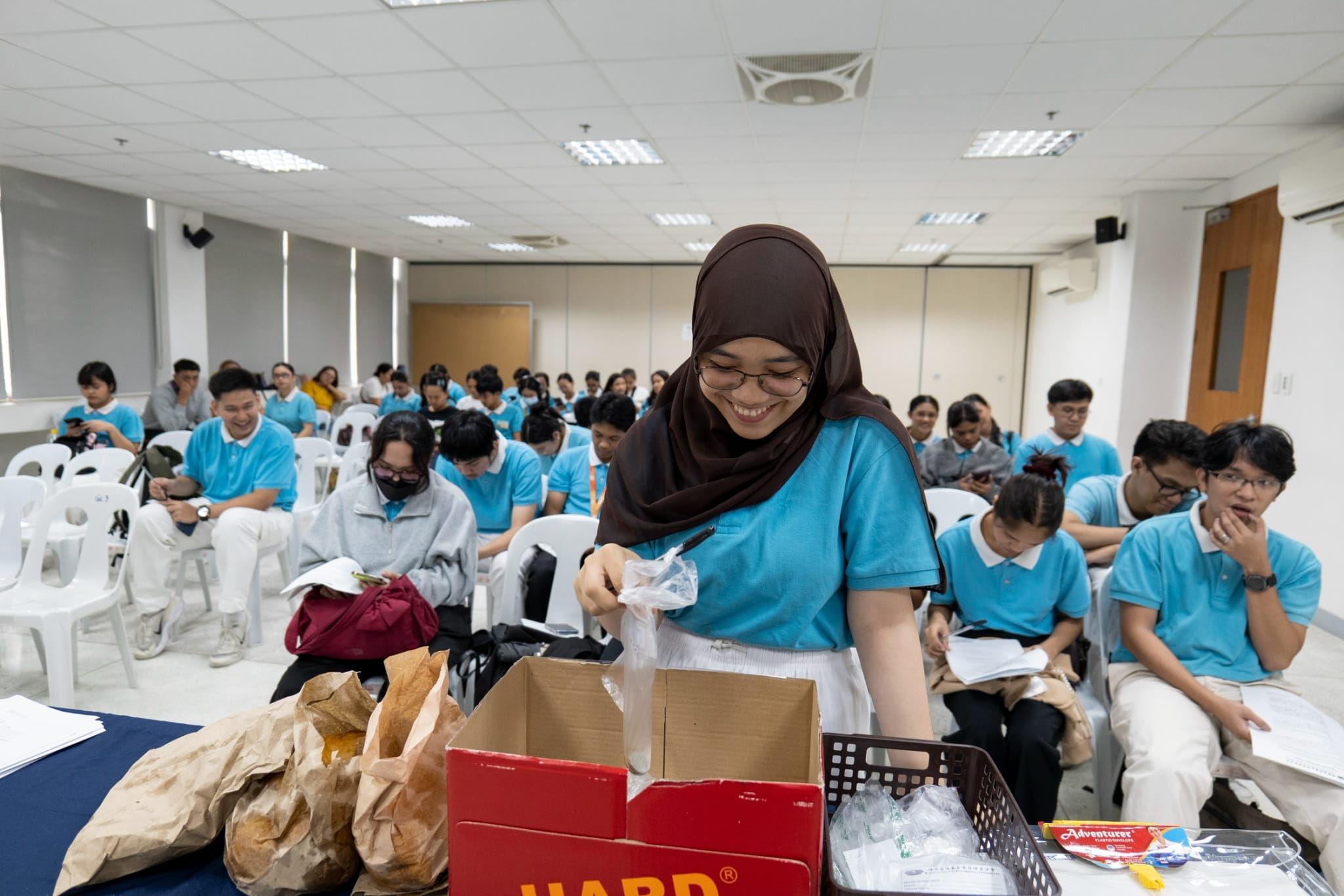 While waiting for their exit interviews, scholars at a holding area drop their pledges for Davao Occidental earthquake victims in a donation box. 