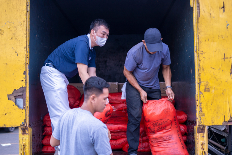 A Tzu Chi volunteer and staff unload the sacks of items from the truck.