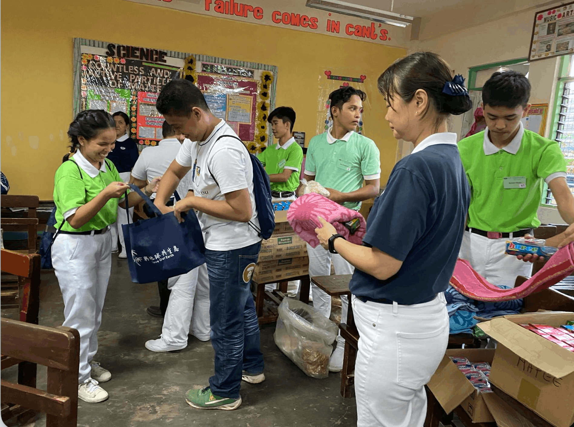 Still in senior high, Andrel (in white) helps Tzu Chi volunteer Marietta Uy (in blue) and scholars pack gift bags for distribution. 