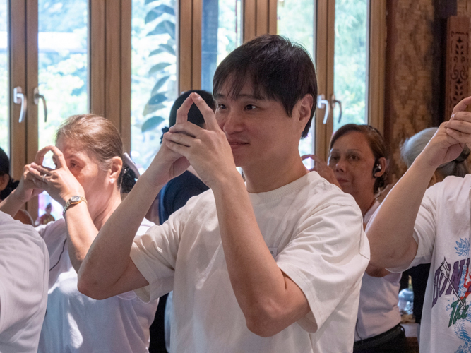 Ken Chua learns the Tzu Chi hand gesture after bowing three times in respect to Dharma Master Cheng Yen and Buddha. 