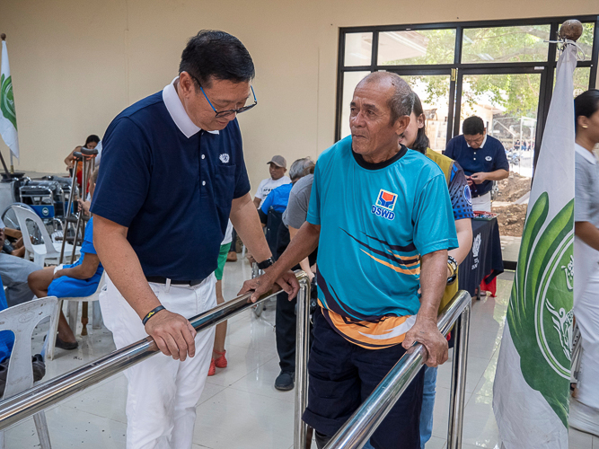 Prosthesis recipient Laurito Imfiel (right) tests out his newly fitted prosthetic leg.