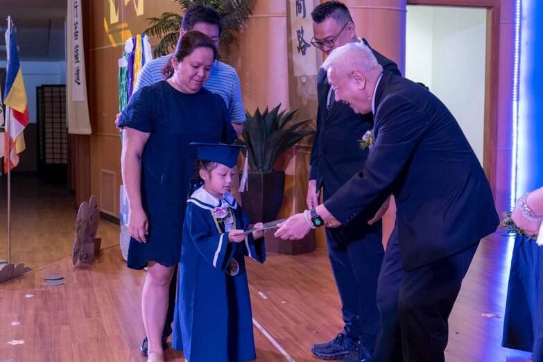 Naiya Lexine Ngo accepts her certificate from Tzu Chi Philippines CEO Henry Yuñez as parents Nikki (in blue dress) and Limarc (in stripes) look on.