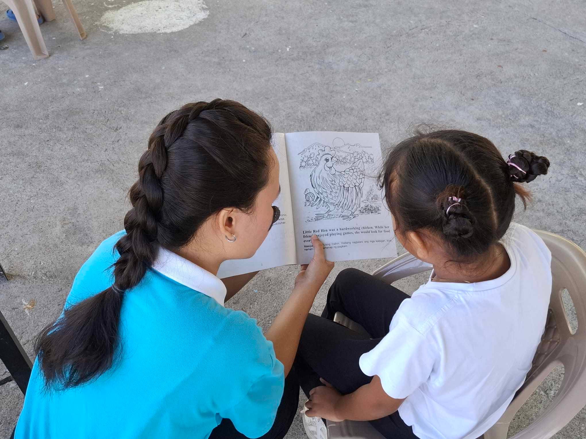 Tzu Chi scholar Nicole Fetalcorin entertains a child at Tzu Chi Great Love Village by reading her a book.