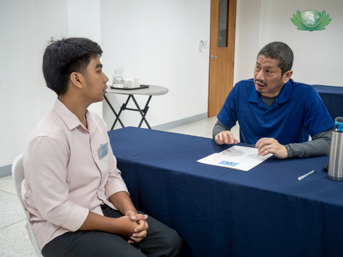 A volunteer interviewer (right) evaluates the scholar’s resumé, asking him questions about the information written.