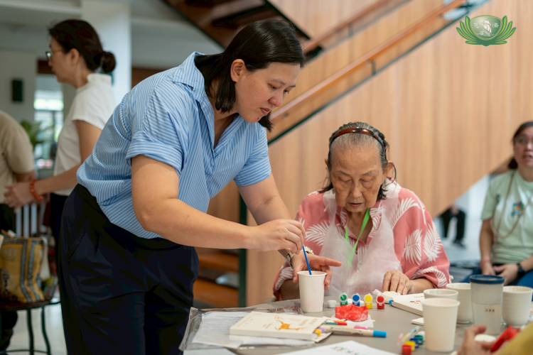 Desiree Llanos Dee (left) assists her mom Lily in painting a clay shape. Before Golden Age Academy, she had never seen her mom paint or sing in public. “She looks forward to coming here every weekend to see everyone and do the activities,” says Desiree.
