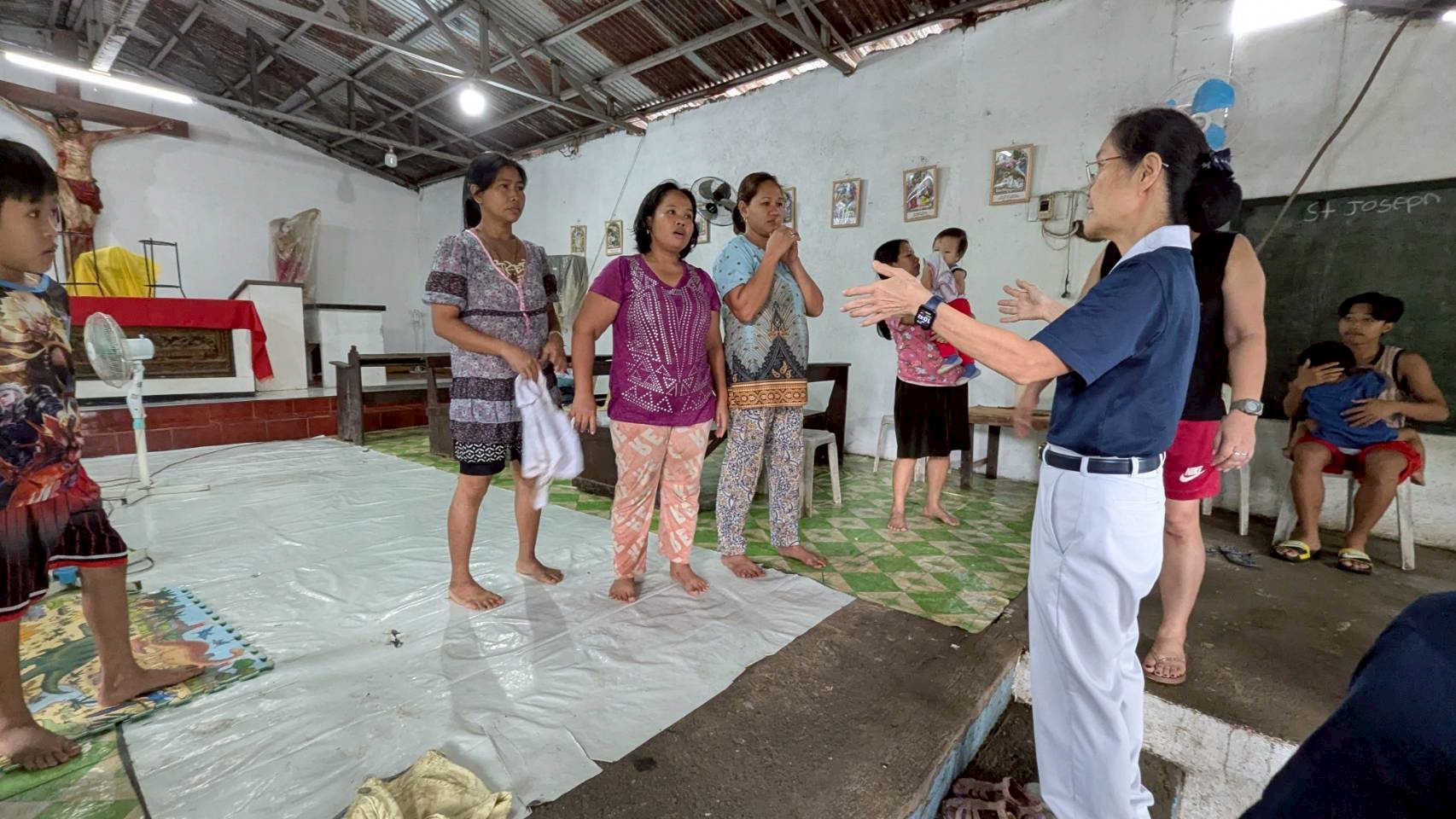 Five families whose homes were damaged by a landslide sought shelter at the St. Joseph the Worker Chapel in San Mateo, Rizal. Tzu Chi volunteer Elvira Chua listens to their stories. 