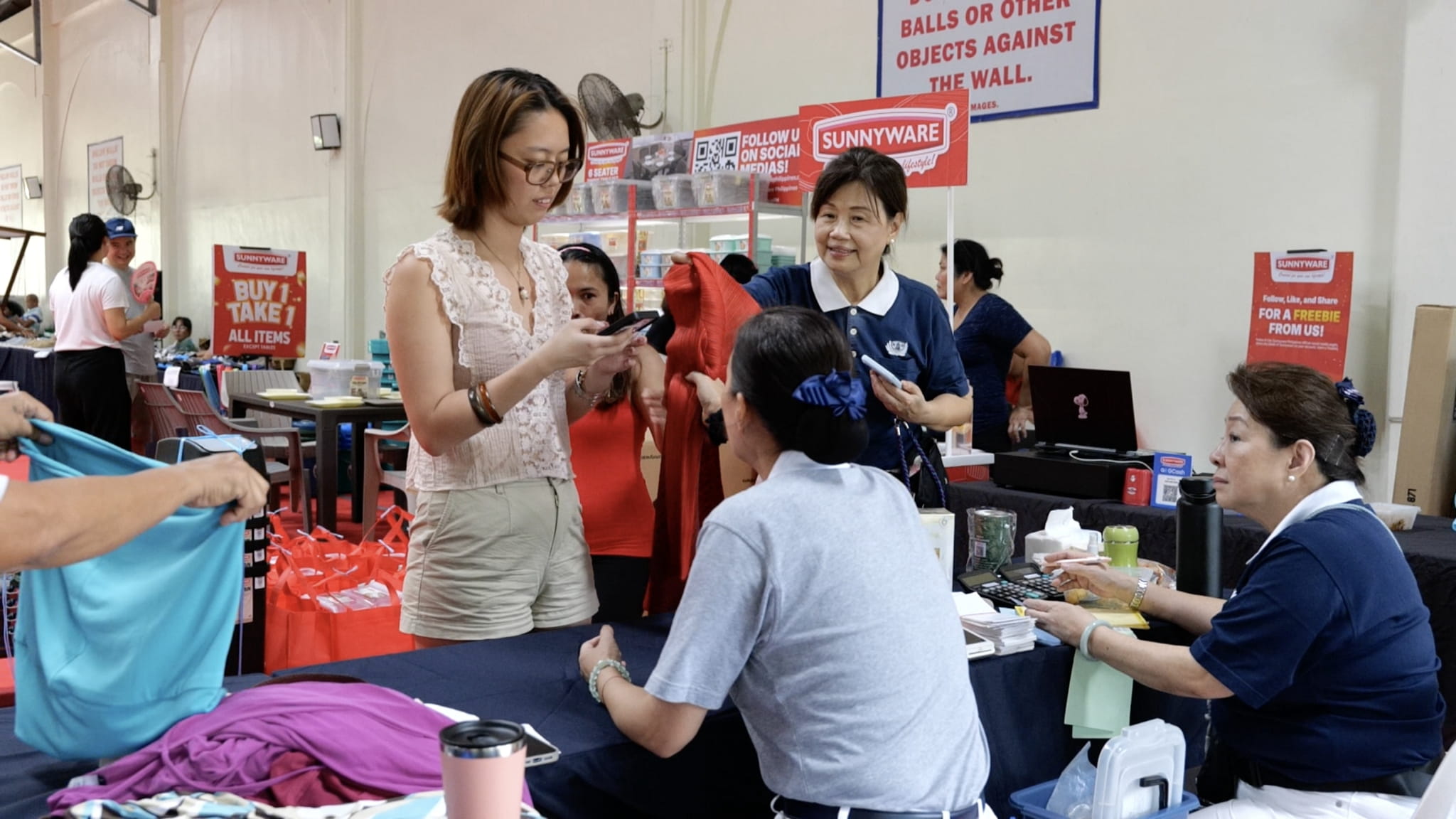 Tzu Chi volunteer Molita Chua (standing, first from right) helps check the clothes at the checkout counter to ensure good condition. 