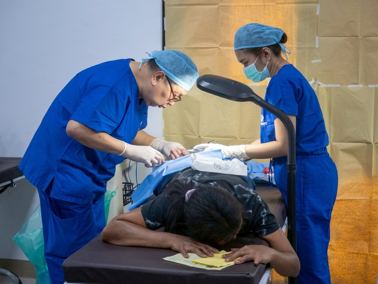 Milagros Lappay Perez lies on her stomach as TIMA surgeons remove a large ball-shaped cyst on her upper right leg, close to her buttocks.