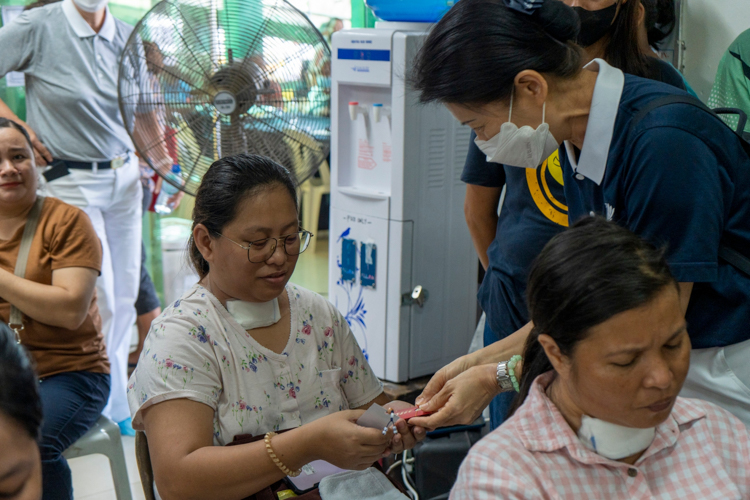 Volunteers distribute tokens from Tzu Chi Founder Dharma Master Cheng Yen—an ampao (red envelope) and an aphorism with a charm.