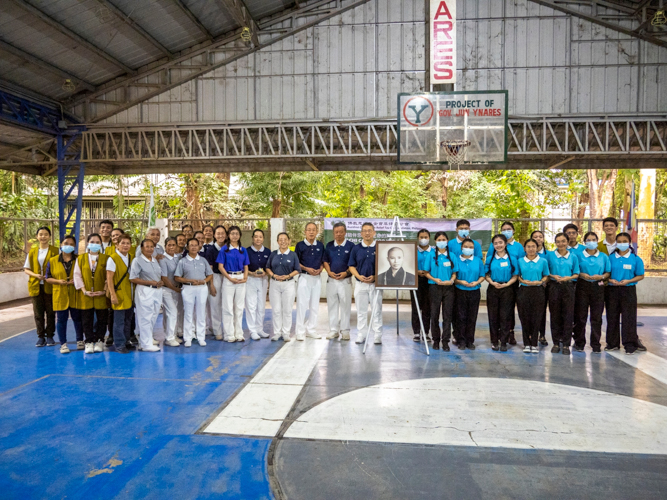 Tzu Chi volunteers and scholars pose with Master Cheng Yen’s portrait at the covered court of Barangay Mambungan.