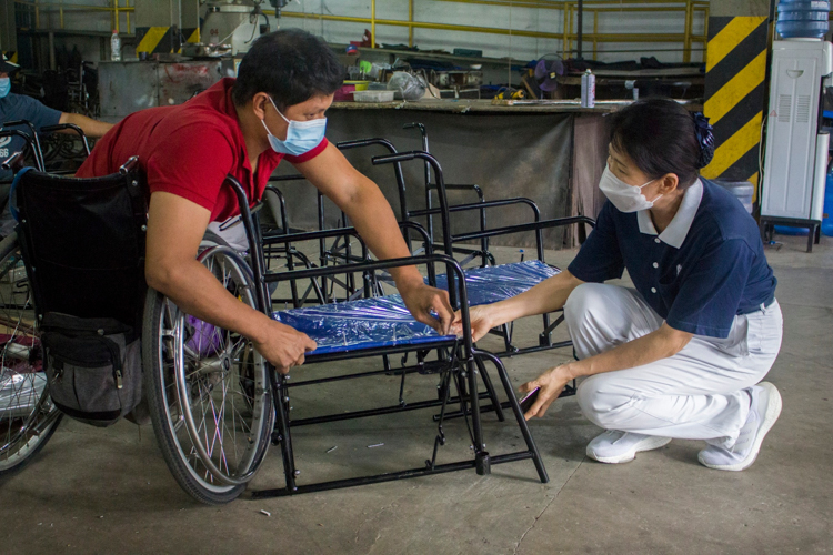 A PWD shows a Tzu Chi volunteer his work so far on a wheelchair. 【Photo by Matt Serrano】