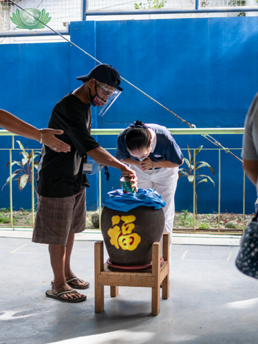 A volunteer bows in gratitude as a scavenger beneficiary drops his collected coins in a jar. 【Photo by Daniel Lazar】