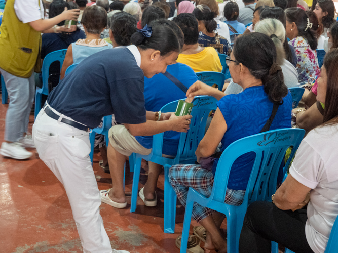 A Tzu Chi volunteer gratefully collects the cash donations of beneficiaries. These funds collected are used to help more people in need of support.