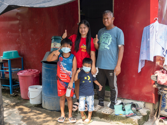 Venus Telecio (back row, first from left), along with her husband and their two children, use a hand gesture of thanks to show their gratitude to the Tzu Chi Foundation.