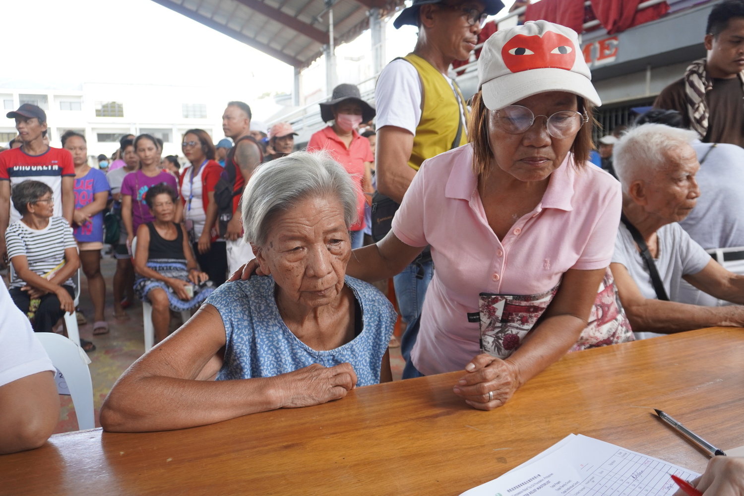 Beneficiaries wait as their names are checked on the list.