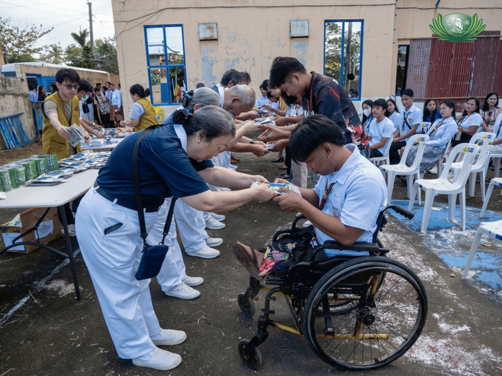 Volunteers bow as they present student beneficiaries with Tzu Chi stickers and aphorisms.