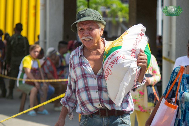 A senior citizen carries his 25-kg sack of rice with ease.