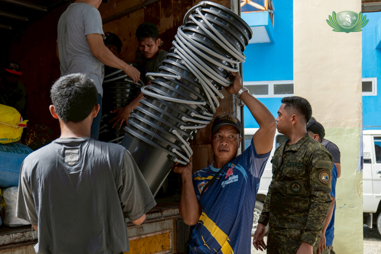 Local barangay workers and members of the Philippine Army help carry donation items, most of which are made from eco-friendly materials.