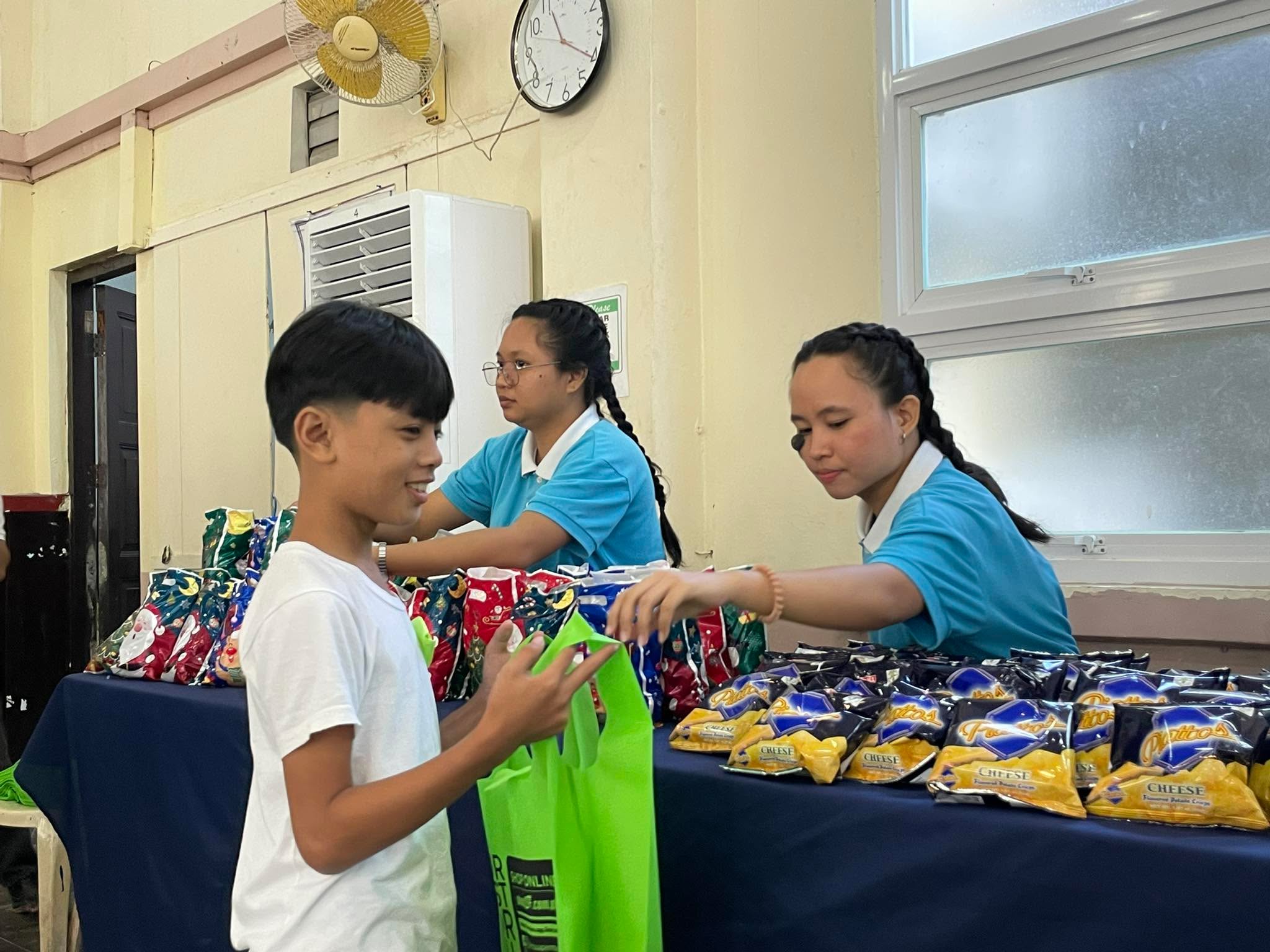 Tzu Chi scholar Nicole Fetalcorin helps hand out snacks for the children in an outreach program.