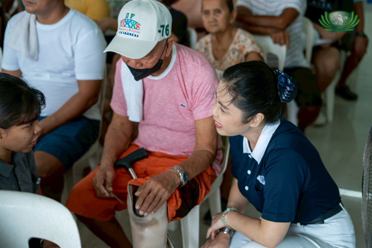 Tzu Chi volunteer Pansy Ho initiates conversation with a beneficiary with a prosthetic limb.