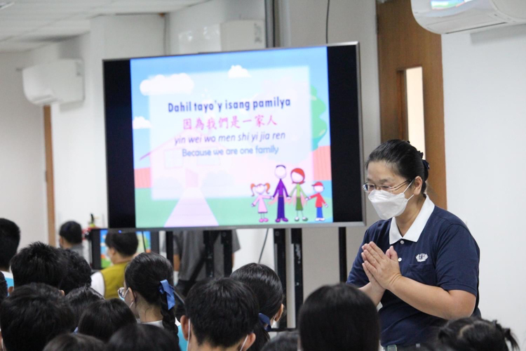 A volunteer leads scholars in the signing and singing of “One Family.” 【Photo by Kenley Yap Wong】