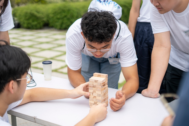 In the spirit of team work, participants help each other make a Jenga tower. 