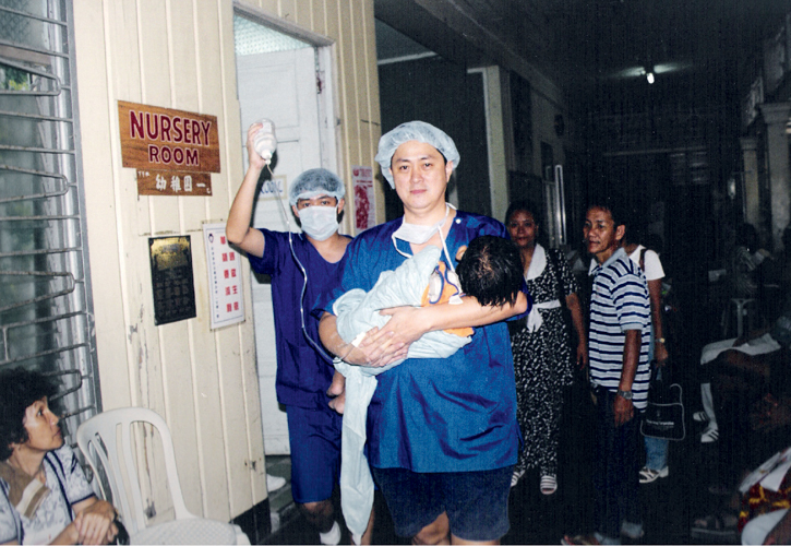 Dr. Jo Qua carries a patient to a makeshift recovery room in a school where a Tzu Chi medical mission takes place. 