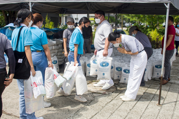 A Tzu Chi volunteer bows before scholars as they claim their two sacks of 10-kg rice. 【Photo by Matt Serrano】