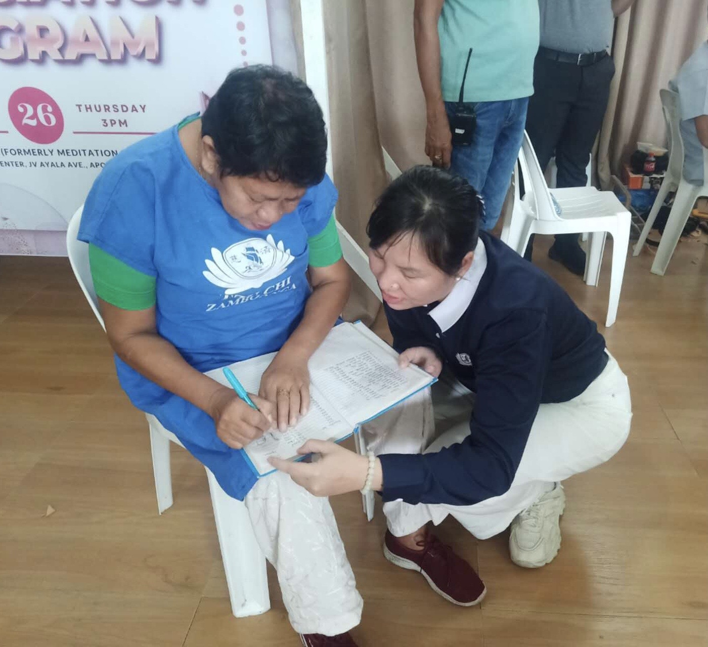 A Tzu Chi volunteer assists a beneficiary in filling up forms. 